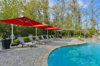 A swimming pool with umbrellas and chairs next to it